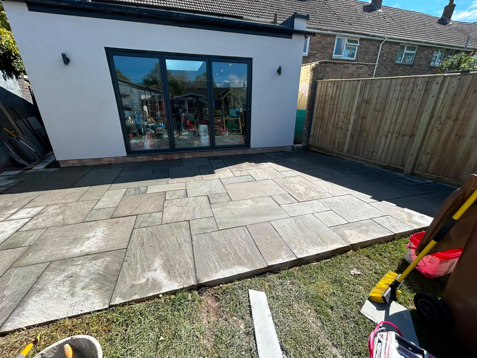 Grey Indian sandstone patio in random block pattern laid to a modern rear extension by DR Smith Building.