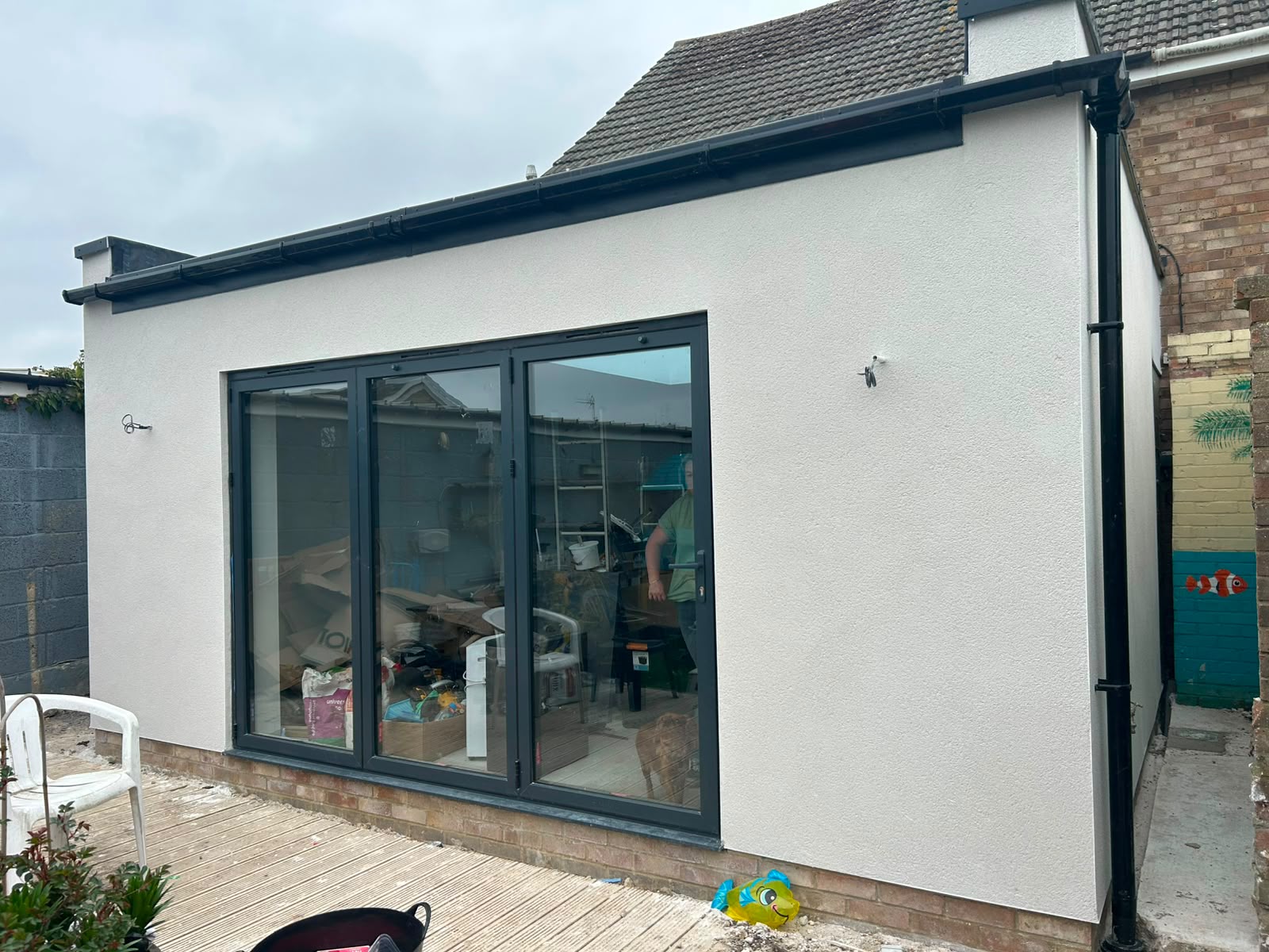 Rear single-storey rendered extension with anthracite aluminium bifold doors, completed by DR Smith Building in Wiltshire.
